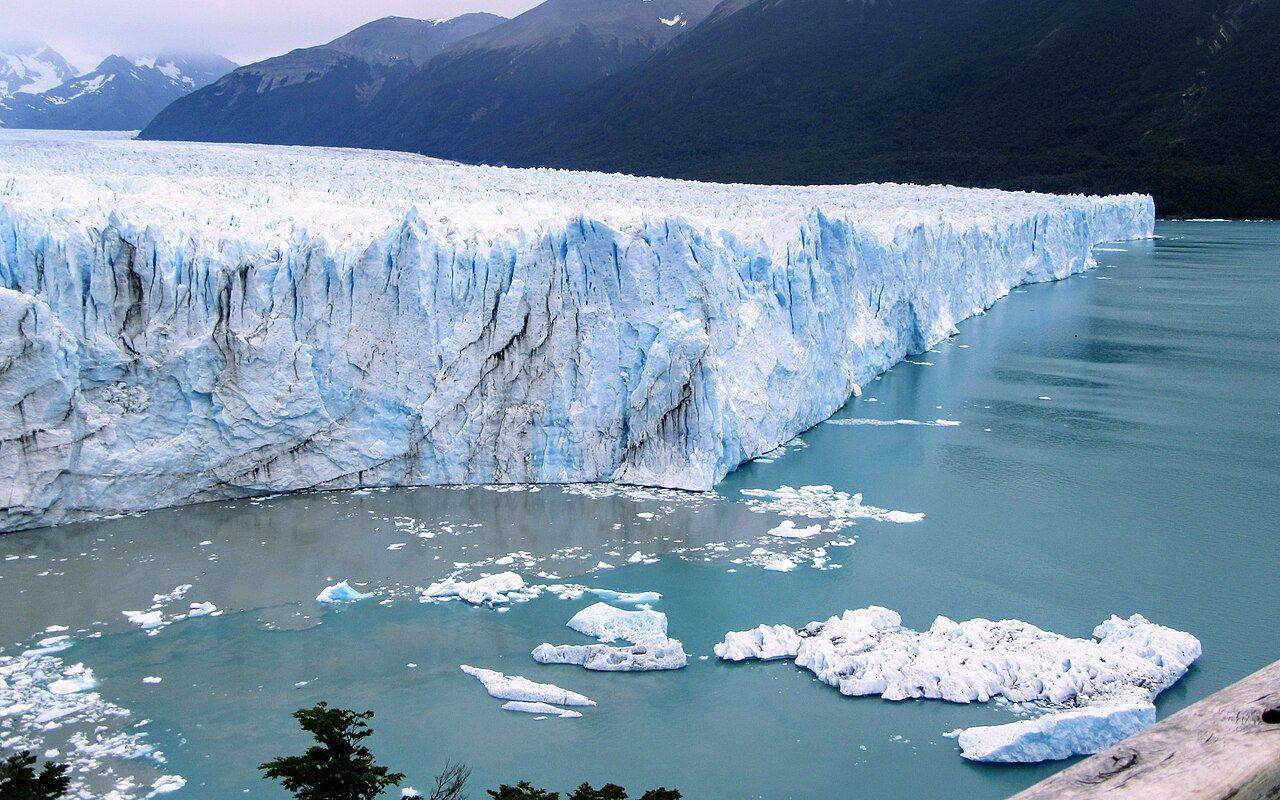Frente del glaciar Perito Moreno, con témpanos en el agua y montañas al fondo.