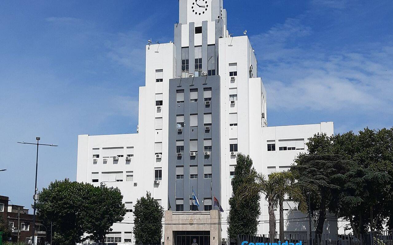 El Palacio Municipal de Lomas de Zamora frente a una plaza con un cartel que dice Comunidad Lomas