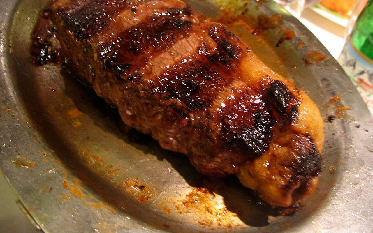 Bife de chorizo cocido servido en una fuente metálica.
