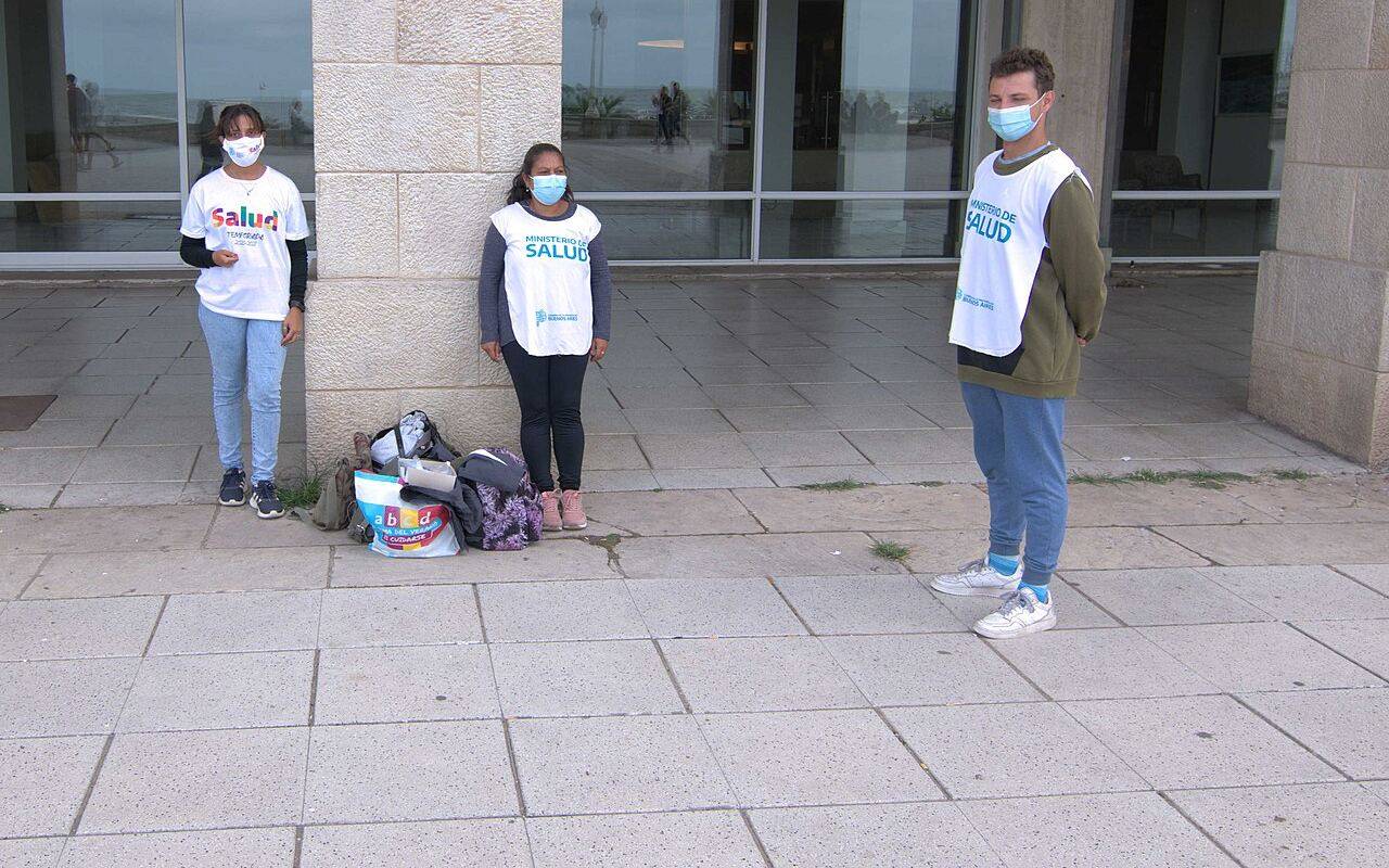 Tres trabajadores con barbijos y pecheras de Salud frente a un edificio.