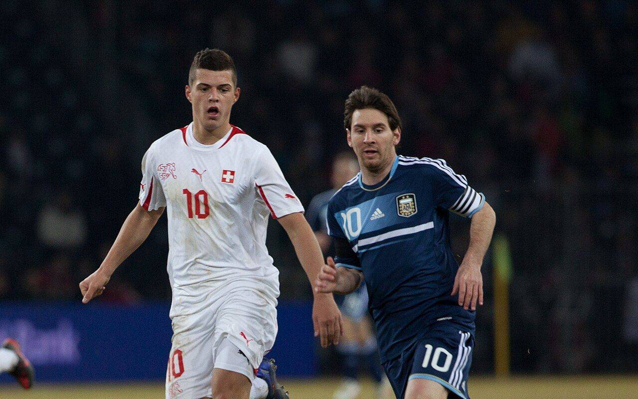 Lionel Messi con la camiseta de Argentina corre junto a Granit Xhaka durante un partido ante Suiza.