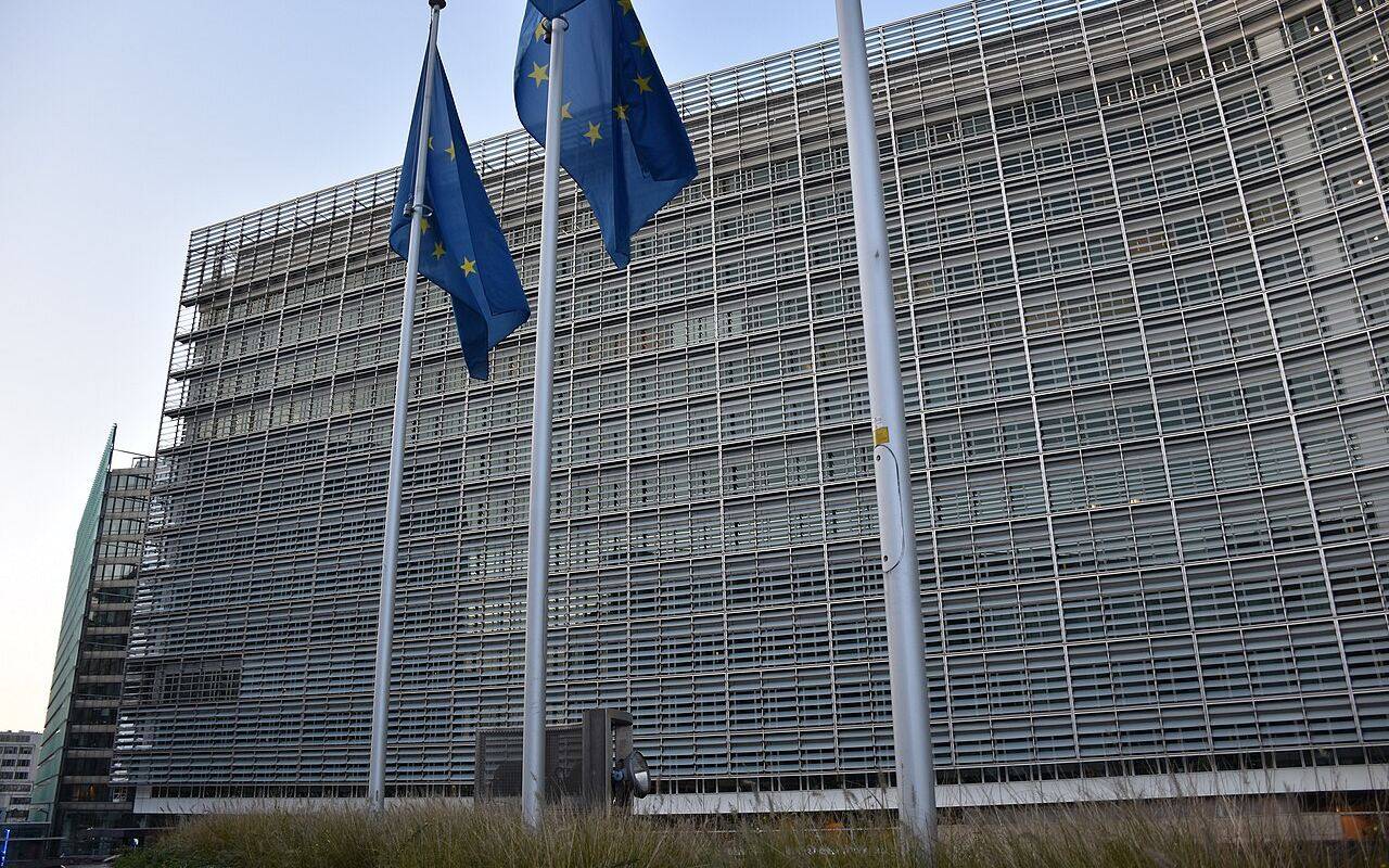 Edificio de la Comisión Europea en Bruselas, con banderas de la Unión Europea en primer plano.