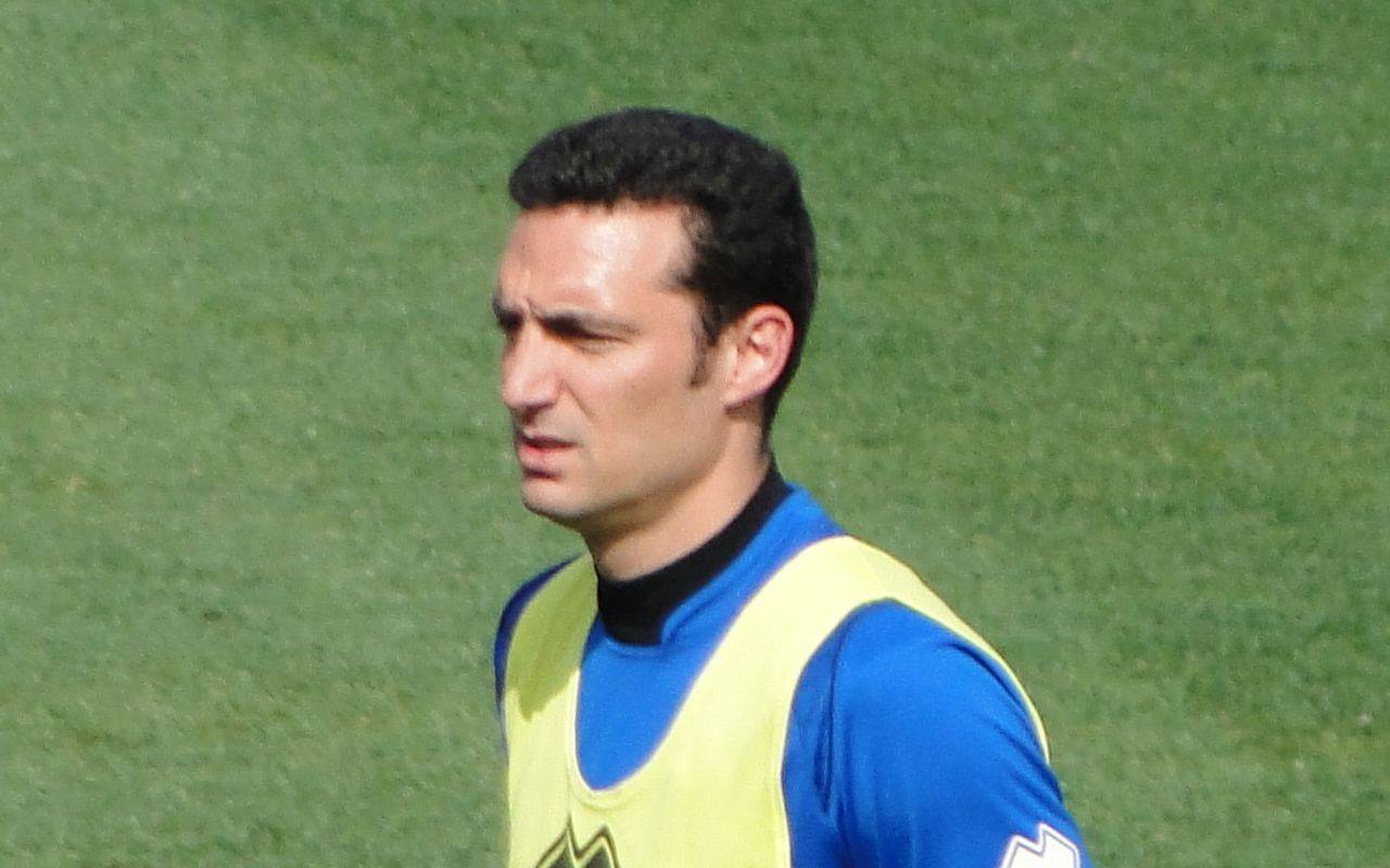 Lionel Scaloni vistiendo ropa deportiva con una pechera amarilla en un campo de entrenamiento